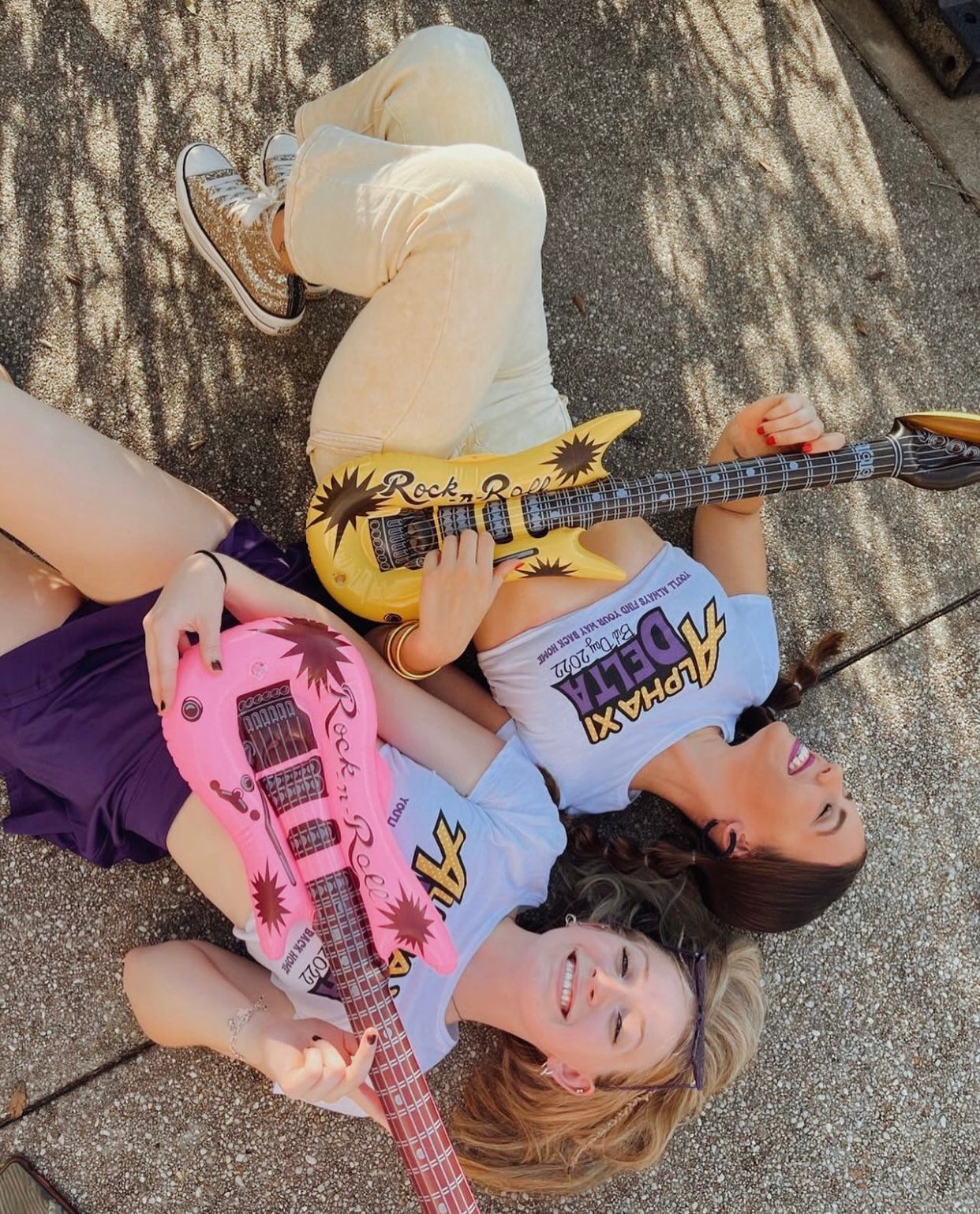 Two girls posing with a guitar wearing sorority clothing